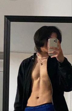 a shirtless man taking a selfie in front of a mirror with his cell phone