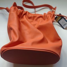 New, Store Overstock. Drawstring Closure Top With Latch. Lined Inside With Two Pockets, One Zippered And One Plain. Adjustable Shoulder Strap. Dimensions Are 11" Long, 11" Tall And 6 Inches Wide With A 40" Long Shoulder Strap. Faux Leather Material, Nylon Lining. Wipe Clean Material Care. Any Questions Please Contact Me. Thanks For Visiting My Poshmark Listing Today. Casual Soft Leather Hobo Bucket Bag, Casual Pouch Bucket Bag For Errands, Casual Soft Leather Bucket Hobo Bag, Chic Orange Bucket Bag For Travel, Casual Soft Leather Bucket Bag For Errands, Casual Soft Leather Bucket Bag, Orange Bucket Bag For Travel, Orange Bucket Bag For Everyday Use, Casual Orange Bucket Bag