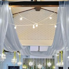 a room with white drapes and chandeliers hanging from the ceiling