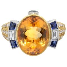 A unique Vintage style, Art Deco Style Yellow 8.02cts citrine engagement ring. Beautiful Yellow Oval Citrine bezel set as a center stone with baguette Blue Sapphires and diamonds on each side, creating a very unique look. More round cut diamonds are pave set on a shank. This piece is crafted in platinum and 18K yellow gold. Blue sapphires total carat weight, 0.54. Diamond total carat weight, 0.62. Ring size 7. Weight: 14.00 grams. Comes with a presentable gift box. Luxury Yellow Gemstones With Accent Stones, Luxury Yellow Oval Sapphire Ring, Luxury Yellow Sapphire Round Ring, Yellow Multi-stone Sapphire Ring, Luxury Yellow Sapphire Ring, Yellow Sapphire Ring With Oval Shape And Accent Stones, Luxury Yellow Ring With Bezel Setting, Luxury Yellow Rings With Bezel Setting, Yellow Sapphire Ring Engagement