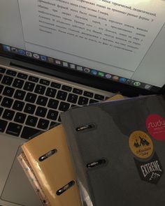 an open laptop computer sitting on top of a desk next to a binder and notebook