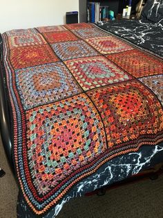 a bed with a multicolored blanket on top of it