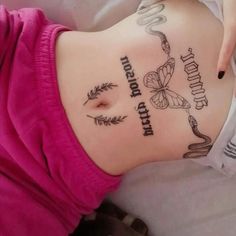 a woman laying down with her stomach covered in tattoos and writing on the side of her body