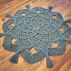 a blue doily with tassels is on the floor next to a wood floor