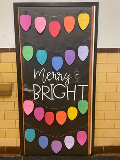 a door decorated with hearts and the words merry bright written on it is in front of a yellow brick wall