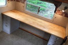 an empty desk in the corner of a room with two windows and drawers on each side