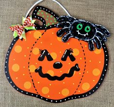 an orange pumpkin with a black spider on it's face and polka dots around the eyes