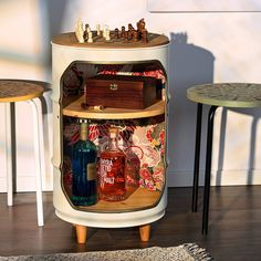 a small cabinet with chess pieces and liquor bottles in it next to two stools