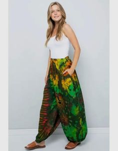 a woman standing in front of a white wall wearing a green and yellow tie dye pants