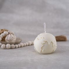 a white candle sitting on top of a table next to beads