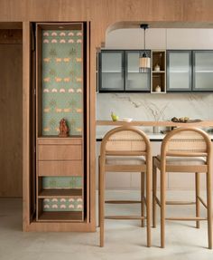 an open cabinet in the middle of a kitchen with two chairs and a table next to it