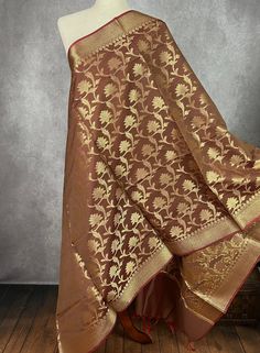 Chocolate Brown Floral Pattern Banarasi Soft Silk Dupatta with Zari Weaved with flower designs all over the dupatta. Please note - The tassels are Red in color Item: DupattaBase color : BrownFabric : Banarasi Silk (Non-Pure Silk)Work : Zari Weaved with tasselsWidth of the dupatta - 35 inches (approx)length of the dupatta - 88 inches (approx) Store Policies- No return or exchange will be accepted for color variations.- No return or exchange will be accepted if the color does not match your other clothing or your partners or anyone else.- Since this Dupatta is handmade hence little inconsistencies may be there however it is not considered as a defect.- Zari or thread coming out at the ends or anywhere on the dupatta or on folds is not considered as defects.- Slight variation in actual color Festive Brown Dupatta With Motifs, Brown Dupatta With Traditional Patterns For Wedding, Brown Wedding Dupatta With Traditional Patterns, Wedding Brown Dupatta With Traditional Patterns, Brown Traditional Wear With Motifs For Festivals, Brown Art Silk Bollywood Dupatta, Brown Traditional Wear With Motifs For Festive Occasions, Brown Bollywood Art Silk Dupatta, Brown Art Silk Dupatta For Wedding