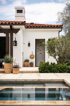 a house with a pool in front of it and potted plants on the side