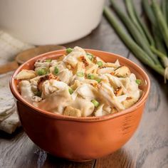 a bowl filled with food sitting on top of a wooden table next to green beans