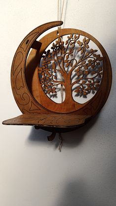 a wooden clock that has a tree on the front and side of it, hanging from a hook