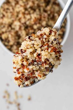 a spoon full of granola on top of a white table with grains in it