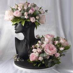 a black mannequin head with pink roses and greenery