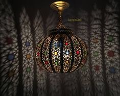 a lamp hanging from the ceiling in front of a wall with many different colored circles on it