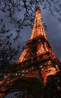 the eiffel tower lit up at night with lights on it's sides