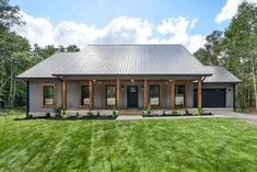 a house with a metal roof in the middle of a grassy area next to trees