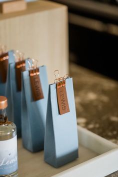 small blue bags with tags on them sitting on a tray next to a bottle of liquor