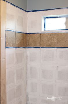 a bathroom that is being remodeled with blue tape on the wall and white tile on the floor