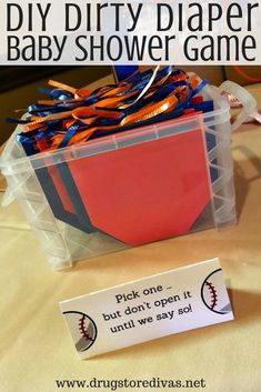 a plastic container filled with orange and blue baby shower game items next to a sign that says, diy dirty diaper baby shower game