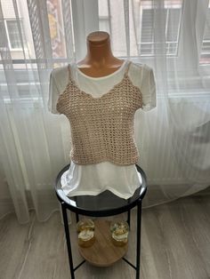 a mannequin wearing a white shirt and some shoes on a stand in front of a window