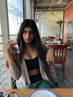 a woman sitting at a table with a glass in her hand