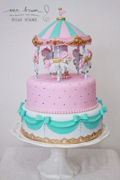 a pink and blue carousel cake sitting on top of a white plate