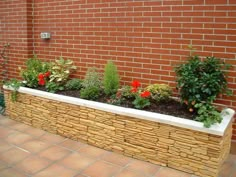 a brick planter filled with lots of plants