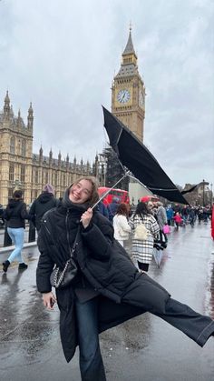 a woman holding an umbrella in front of big ben and the houses of parliament on a rainy day