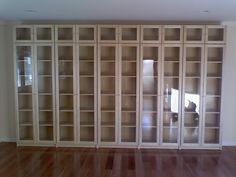 an empty room with wooden floors and large bookcases on the wall behind glass doors