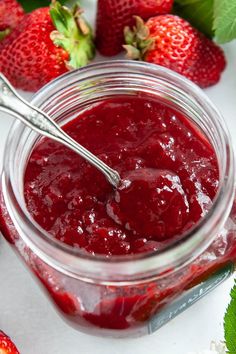 a jar filled with strawberry jam next to fresh strawberries