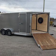 an enclosed trailer parked in a parking lot with the door open and ramp up to it's side