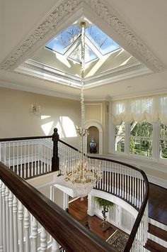 a staircase leading up to a skylight in a large room with white railings