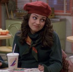 a woman sitting at a table with a drink