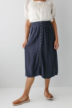 Start your day in style with the 'Greta' Skirt! This midi length, linen-blend skirt is light and airy for spring and summer and features button-down detailing for a fun touch. Pair the 'Greta' with all your favorite tops for Sunday morning or a day at the farmer's market! 30% Linen 70% Rayon Hand Wash Cold Hang to Dry Low Iron if Needed Do Not Dry Clean Fully Lined Model in Ochre Height 5'5" | Wearing Size Small Wearing 'Shalom' Geometric Print Top in Tan & 'Greta' Linen Blend Midi Skirt in Ochre Model in Ochre & Dark Blue Height 5'8" | Wearing Size 1X Wearing 'Sybil' Embroidered Square Neck Top & 'Greta' Linen Blend Midi Skirt in Ochre Wearing 'Shalom' Geometric Print Top in Tan & 'Greta' Linen Blend Midi Skirt in Dark Blue Model in Dark Blue & Black Height 5'9" | Wearing Size Small Weari Summer Midi Skirt In Rayon, Linen Flowy Skirt For Vacation, Summer Midi-length Rayon Skirt, Summer Midi Length Rayon Skirt, Flowy Linen Skirt For Vacation, Knee-length Summer Bottoms With Buttons, Summer Linen Skirt For Day Out, Casual Linen Skirt For Vacation, Spring Vacation Linen Skirt