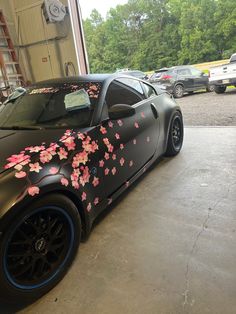 a black sports car with pink flowers painted on it's side in a garage