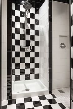 a black and white bathroom with checkered tile on the shower wall, flooring and walls