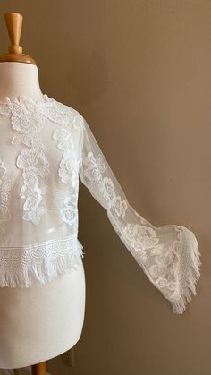 a mannequin wearing a white blouse with lacy sleeves and lace trims on it