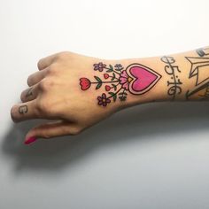 a woman's arm with tattoos on it, and the word love is written in pink