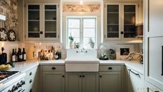 a kitchen filled with lots of counter top space and white cabinets next to a window