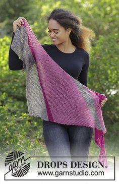 a woman is walking in the woods with a pink and gray shawl on her shoulder