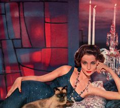 a woman sitting on a couch with a cat next to her and candles in the background