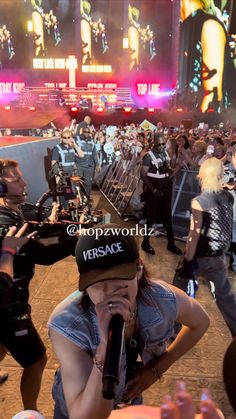 a woman holding a microphone in front of a crowd at a music festival on stage