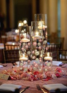 a table topped with lots of tall vases filled with candles