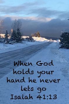 a snow covered road with the words when god holds your hand he never lets go