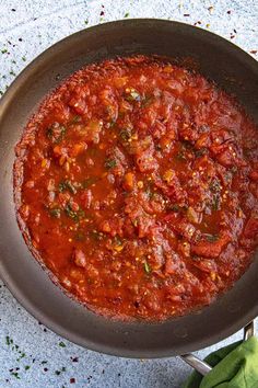 a pan filled with sauce sitting on top of a table next to a green napkin