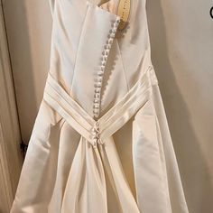 a white dress hanging on a door with buttons and pearls attached to the back of it